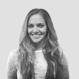 A woman with long hair is smiling in a black and white photo.
