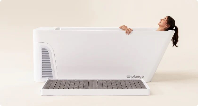 Woman peeking over a giant white bathtub with a beige bathroom floor and wall paneling