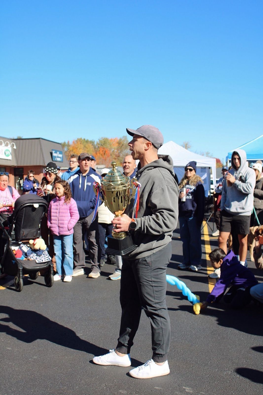 Event host holding a gold trophy while announcing awards to a crowd of families