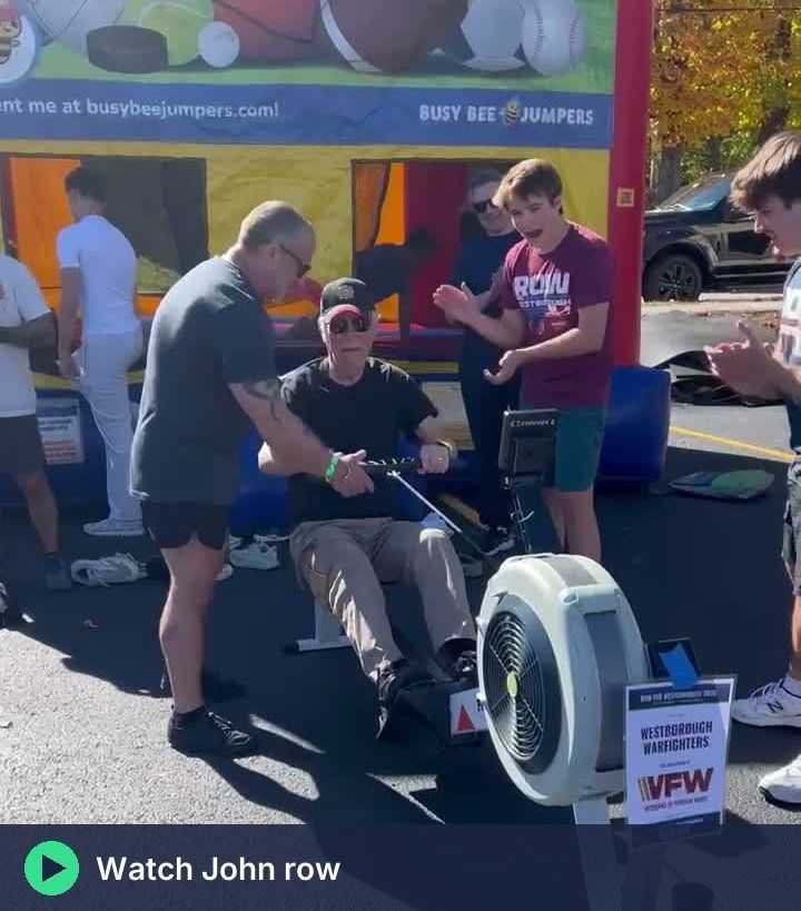 John Gallinagh rowing on the Westborough Warfighters erg with Coach Tony beside him
