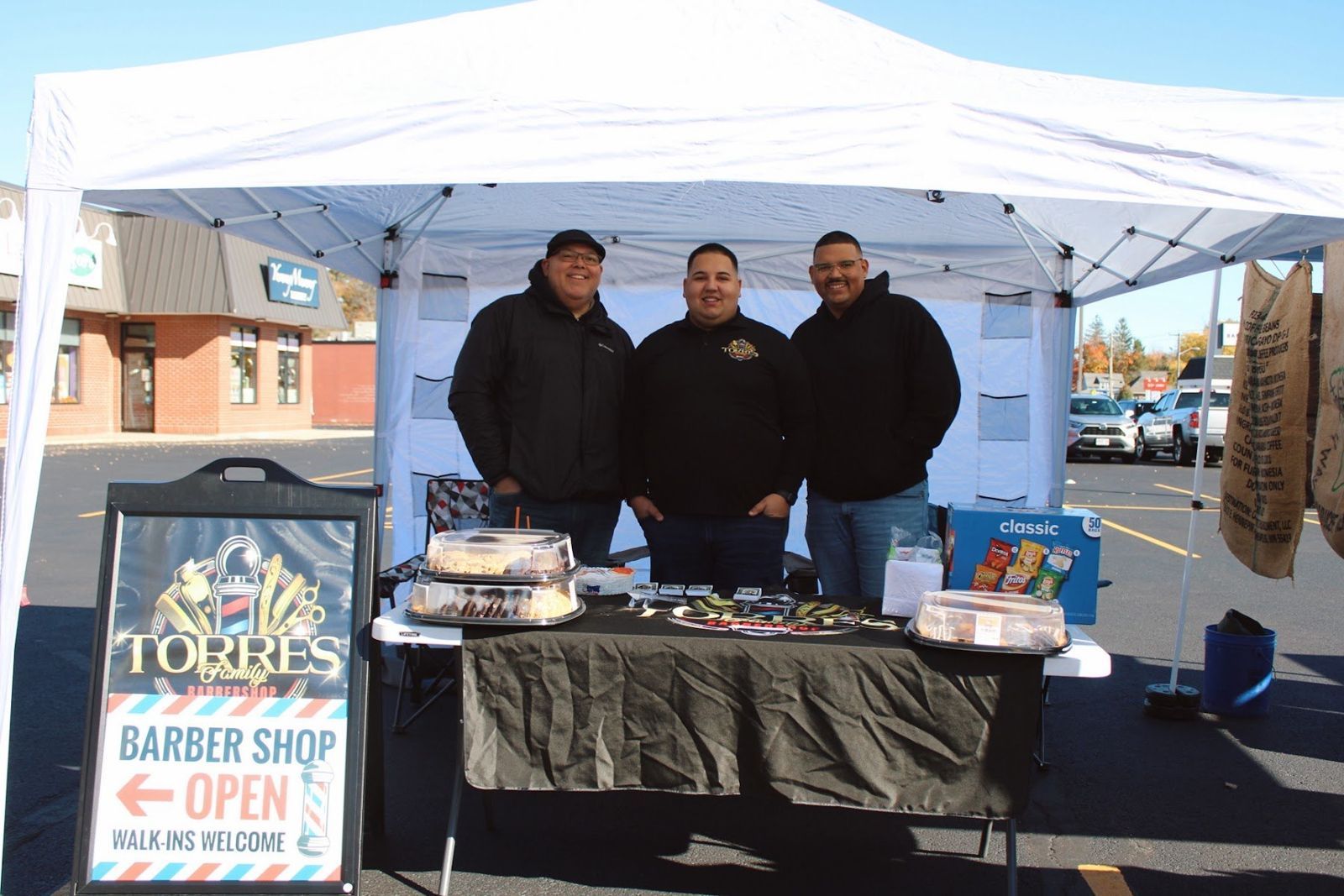 Torres Family Barbershop team standing behind their vendor table