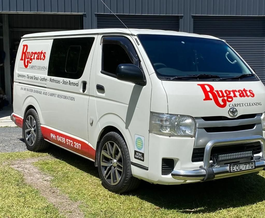 A Man is Cleaning a Carpet With a Vacuum Cleaner — Rugrats Carpet Cleaning Service In Old Bar, NSW