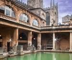 Roman Baths in Bath, England; green water, stone architecture, cathedral in background.