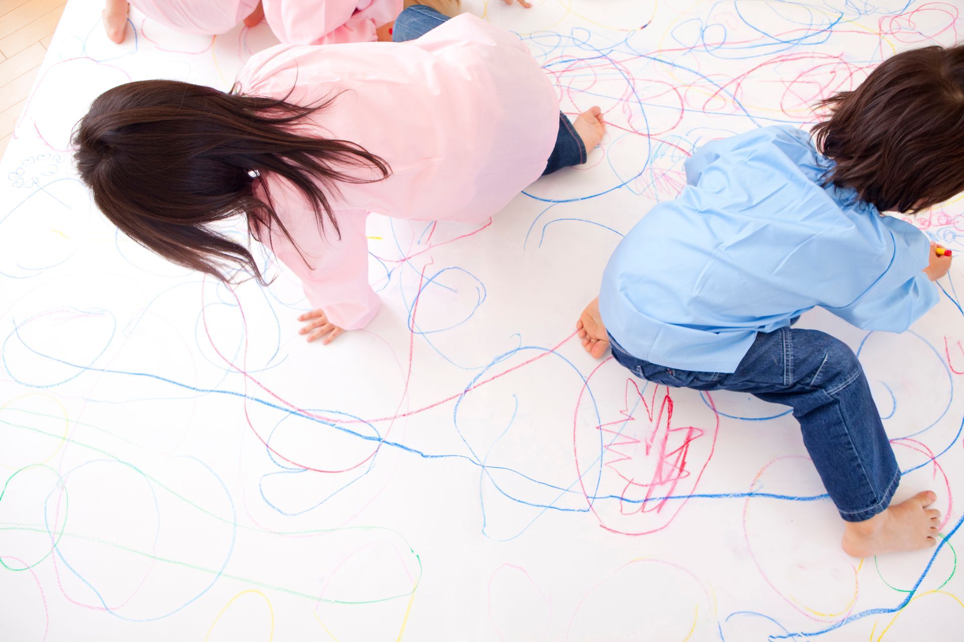 Un gruppo di bambini sta disegnando su un foglio bianco.