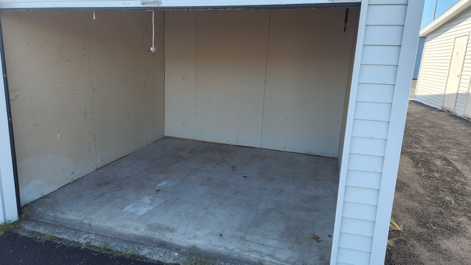 Empty storage unit with an open doorway. The interior has tan walls and a concrete floor. Empty storage unit with an open doorway. The interior has tan walls and a concrete floor.