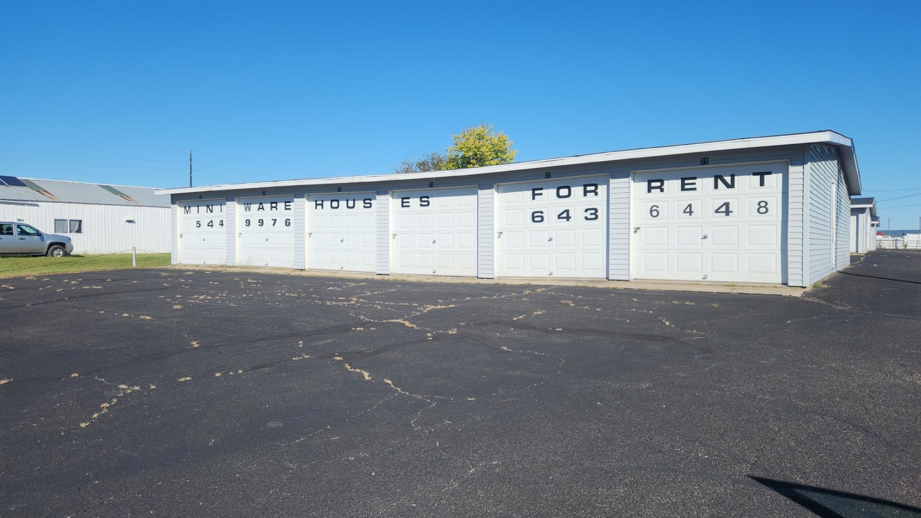Storage units for rent on a sunny day. Gray concrete buildings with black asphalt parking lot. Storage units for rent on a sunny day. Gray concrete buildings with black asphalt parking lot.