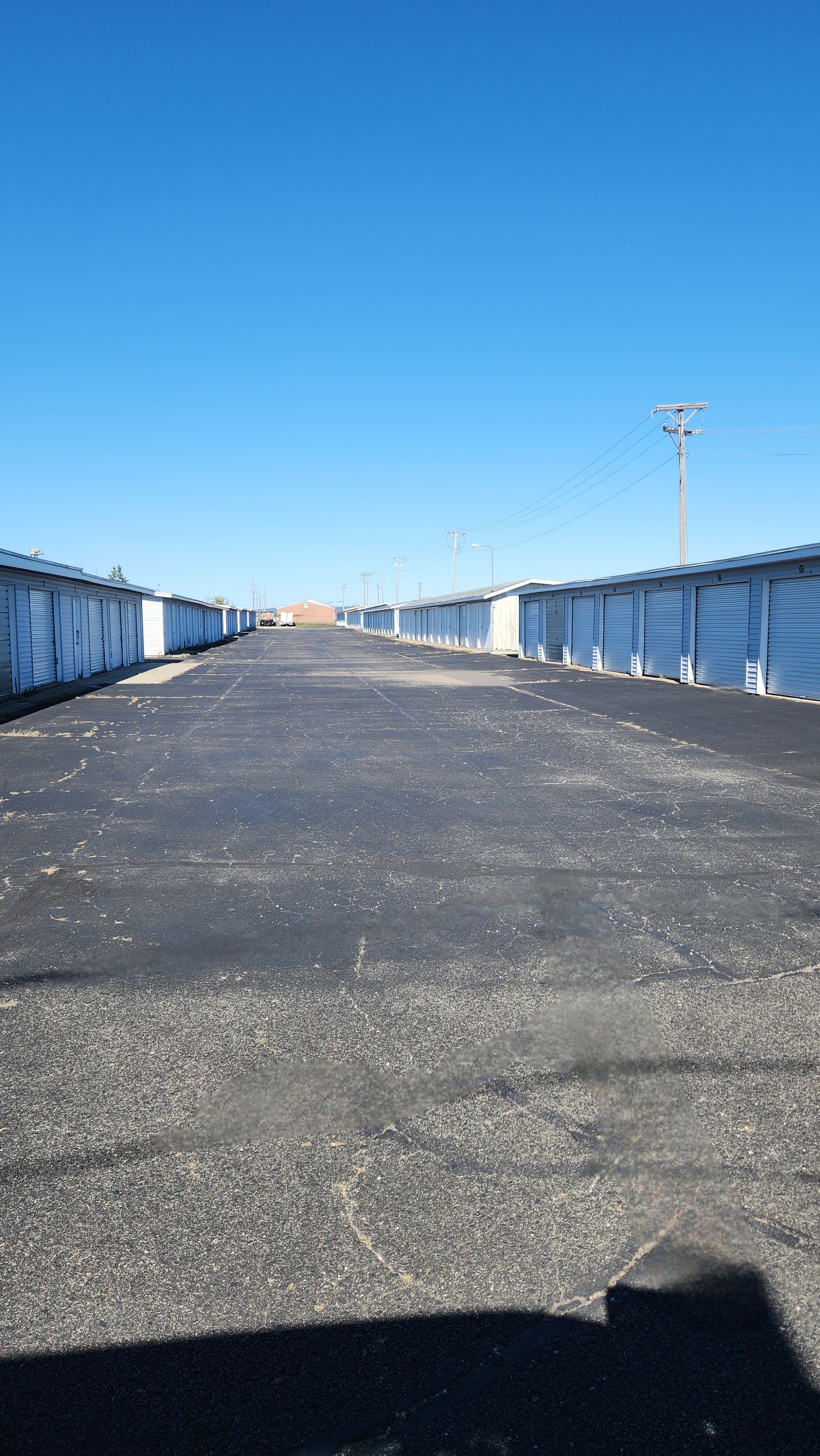Rows of storage units with dark asphalt path, bright blue sky. Rows of storage units with dark asphalt path, bright blue sky.