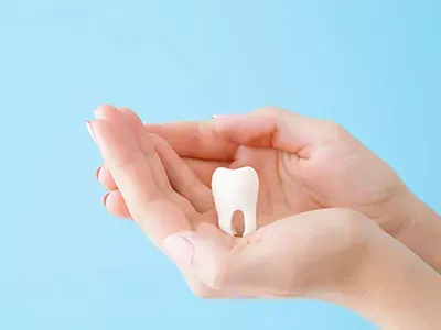 An extracted tooth held in a gloved hand.
