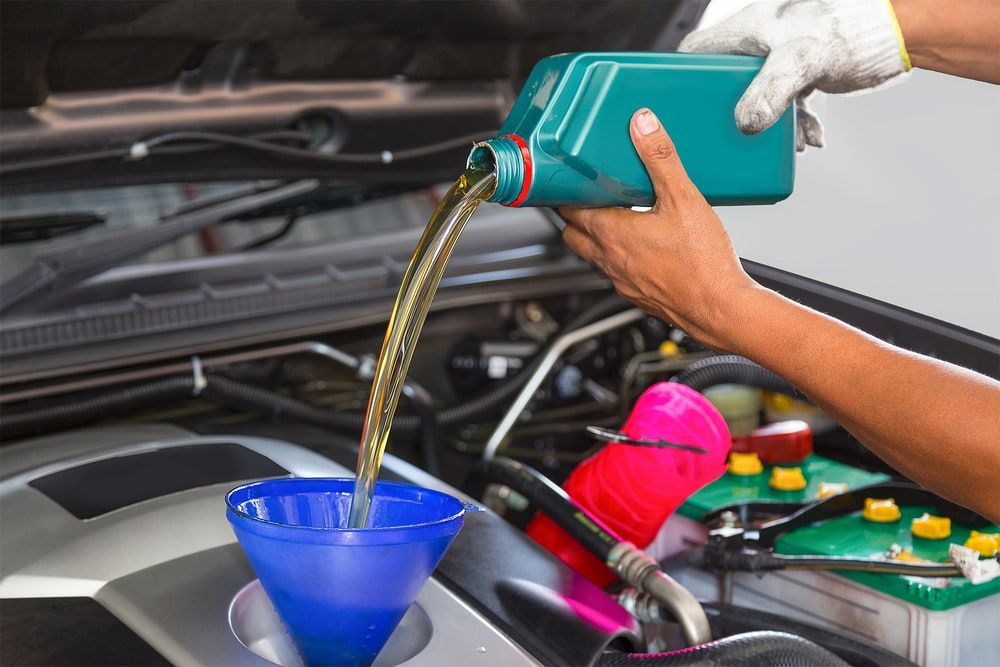 A Person Is Pouring Oil Into A Car Engine — Ag Auto Spark in Narromine, NSW