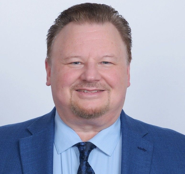 Portrait of a smiling man in a blue suit and tie against a light background