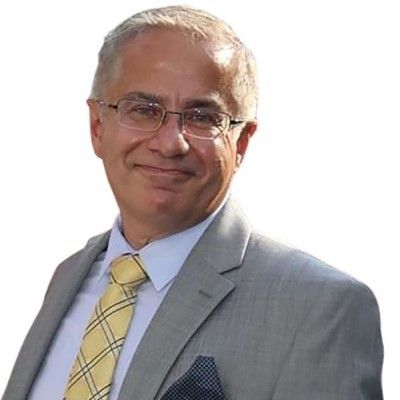 Smiling man in a gray suit and yellow tie against a white background