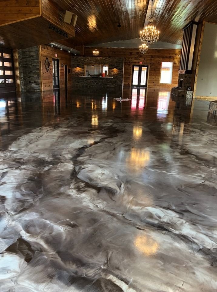 Piso epoxi brillante con diseño metálico que refleja el interior revestido de madera de un gran espacio para eventos.