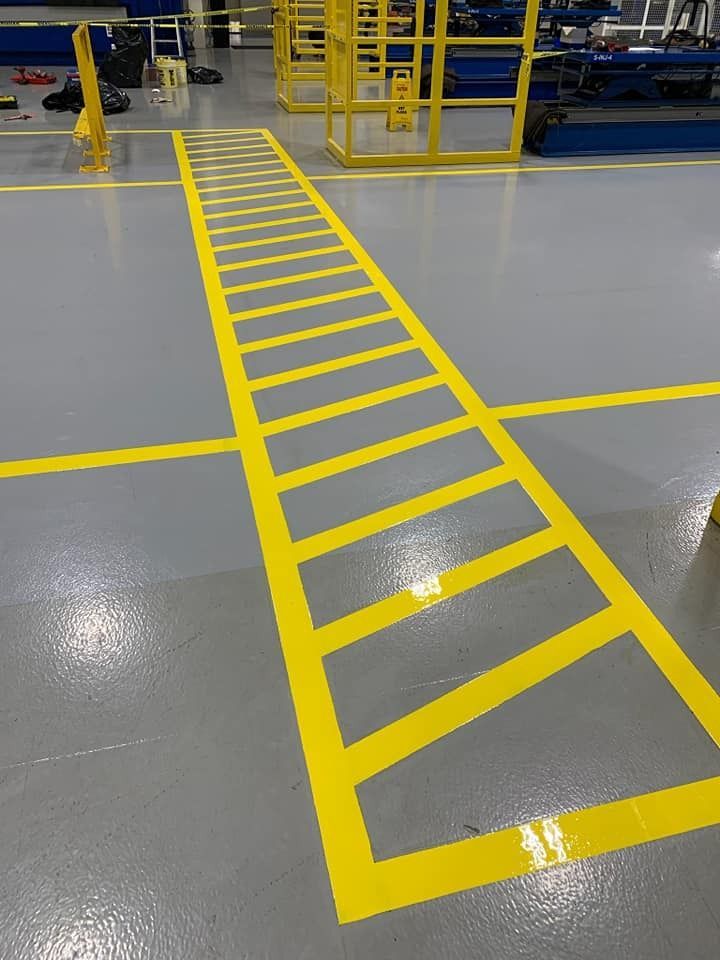 Marcas de suelo de color amarillo en un entorno industrial: un diseño de escalera que cruza un suelo gris, lo que indica una pasarela.