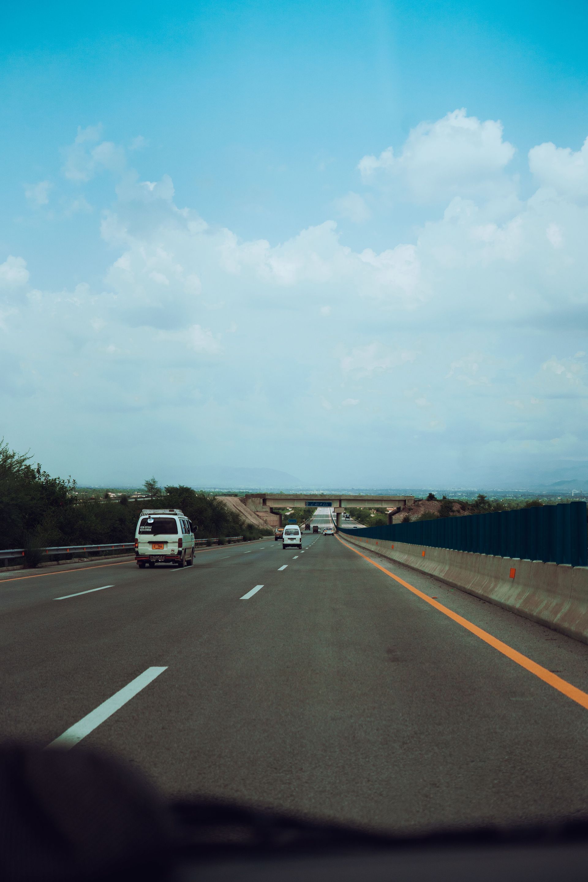 Highway scene with cars driving under a bright blue sky and scattered clouds