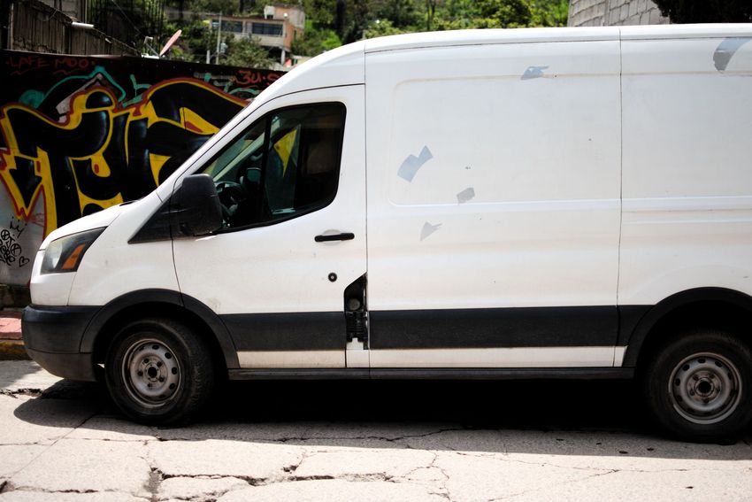 White cargo van parked beside a graffiti-covered wall on a city street