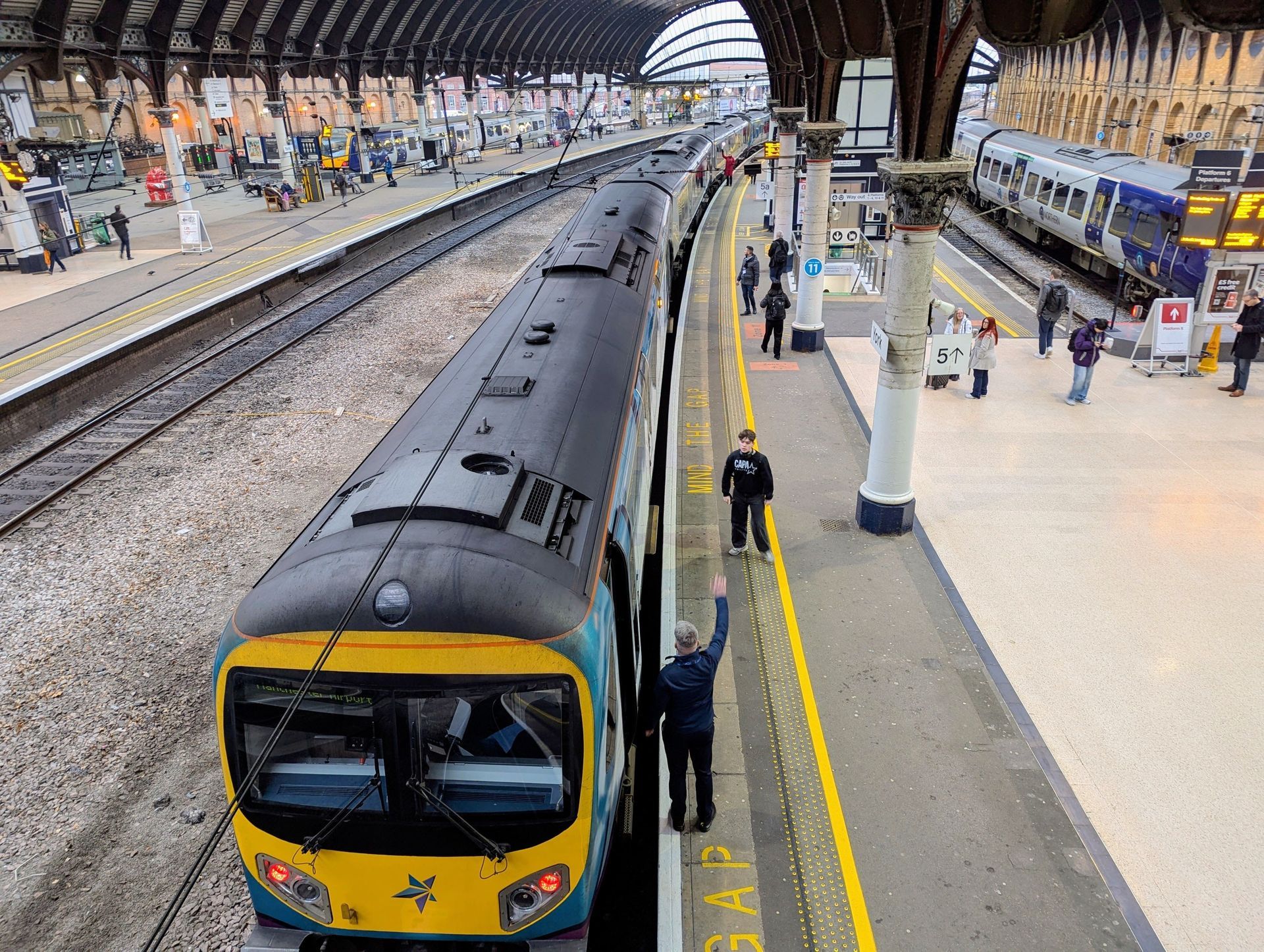 Train at a busy indoor station platform with passengers and multiple tracks visible