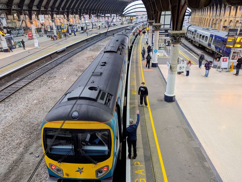Train at a busy indoor station platform with passengers and multiple tracks visible
