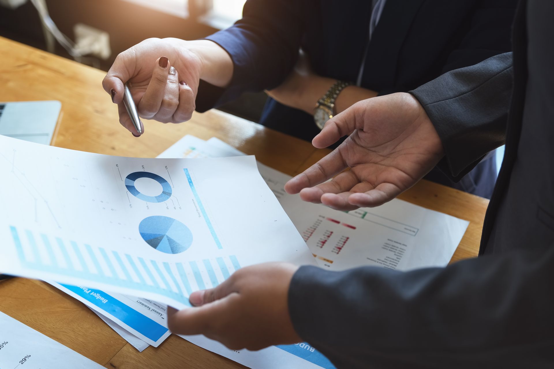 Hands reviewing printed charts and graphs during a business meeting
