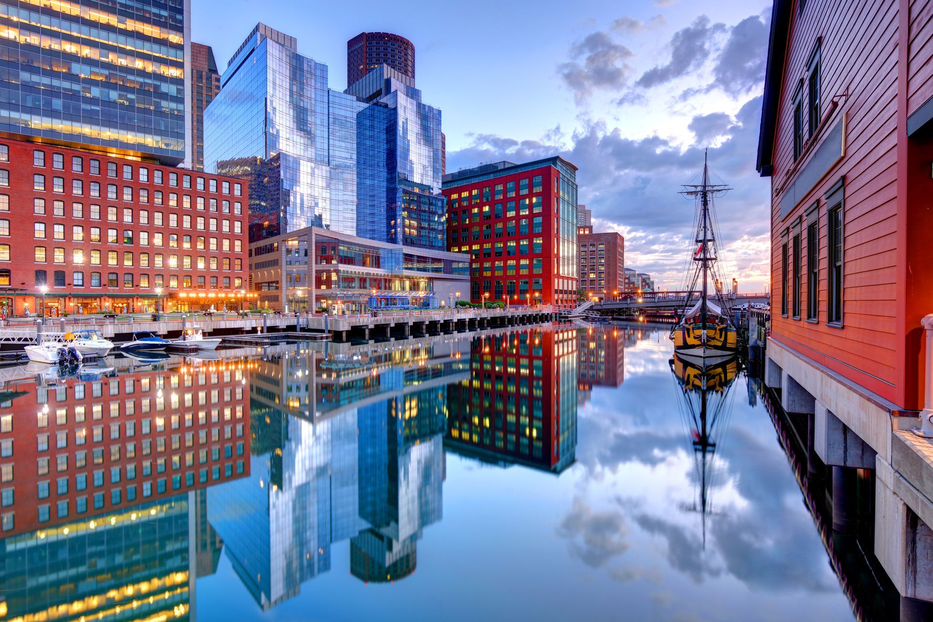 A city skyline is reflected in the water of a harbor.