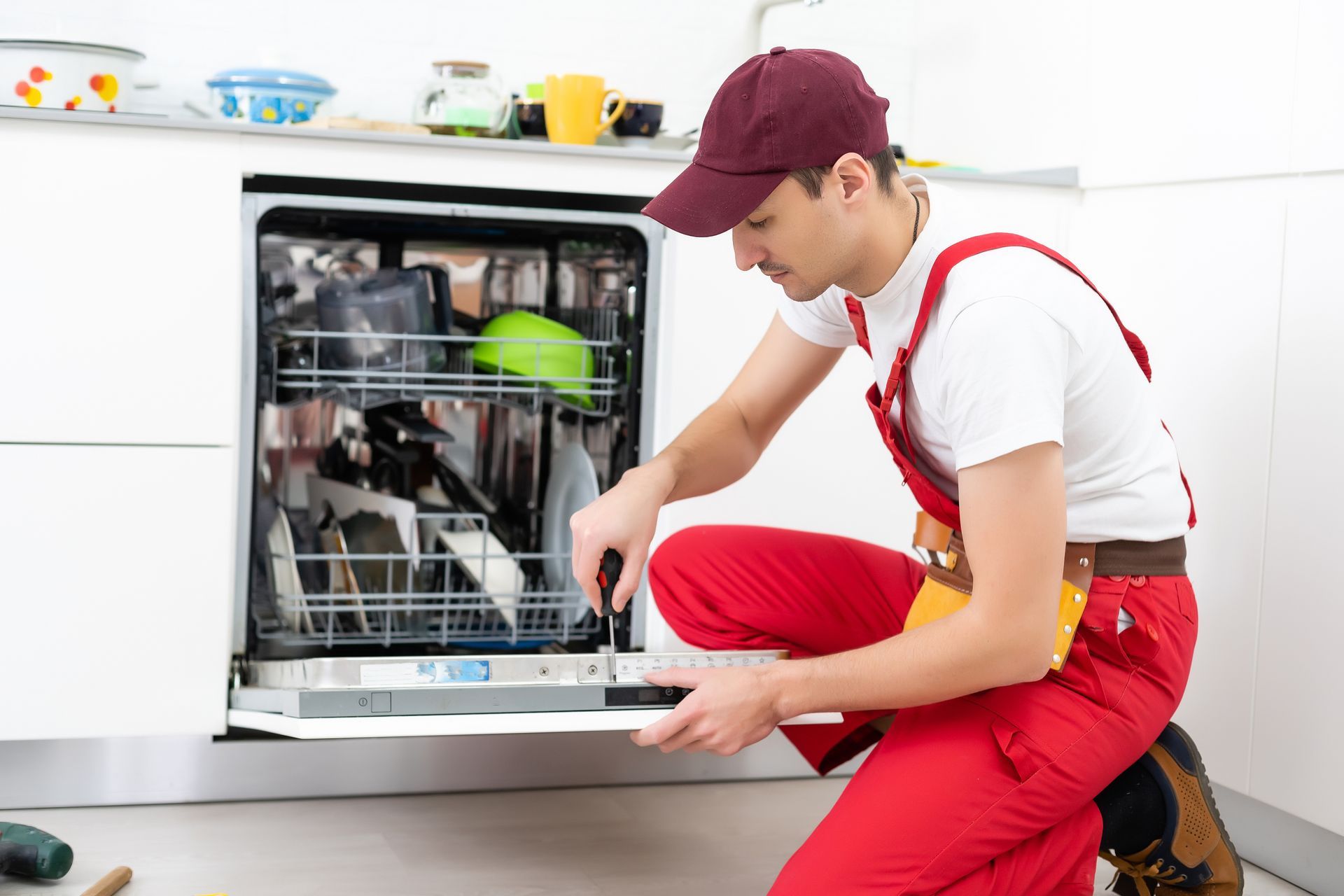 A man is fixing a dishwasher in a kitchen.