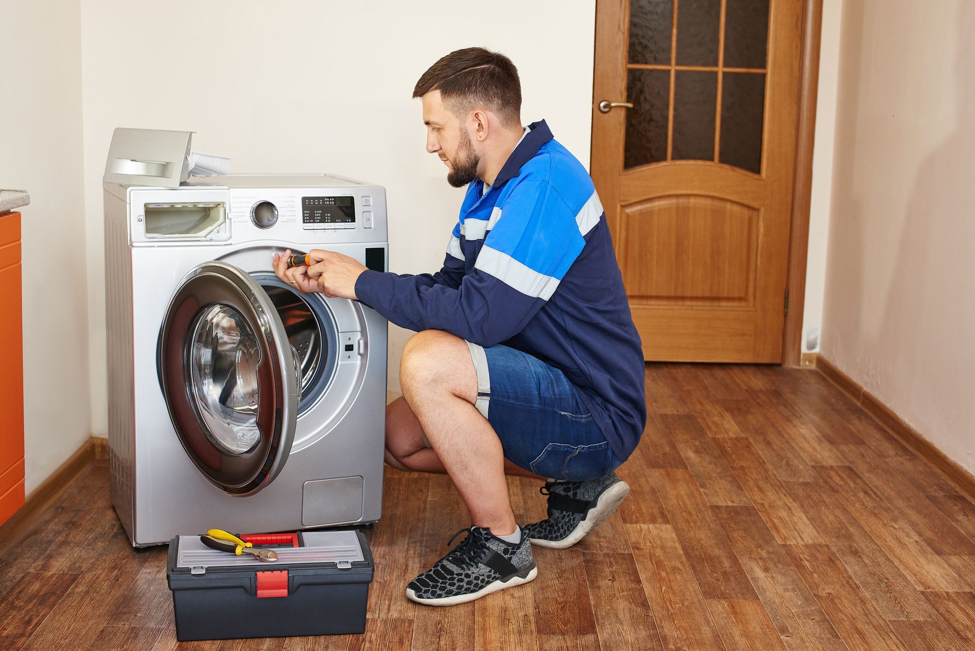 A man is fixing a washing machine in a room.