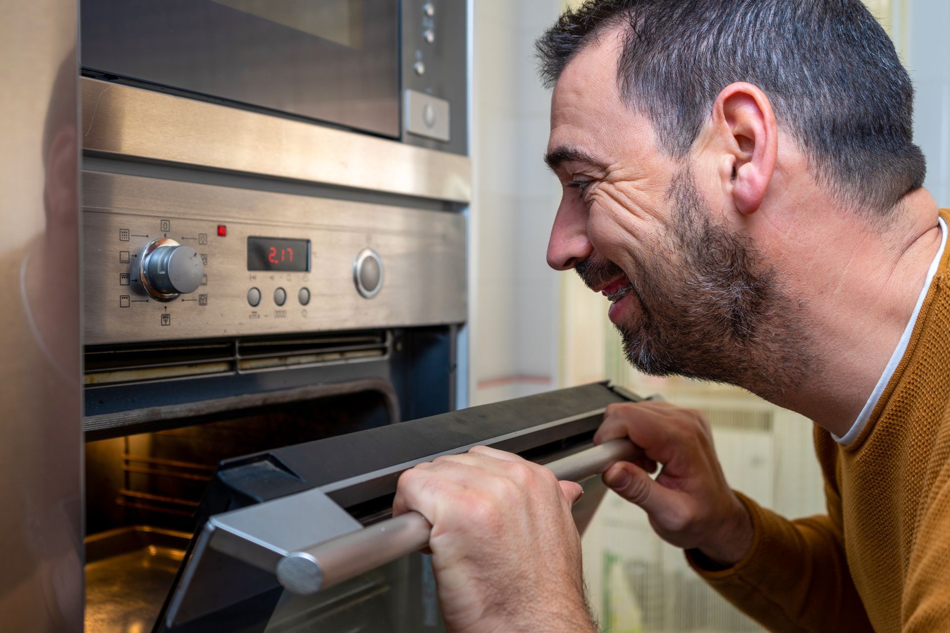 A man is looking into an oven with his mouth open.