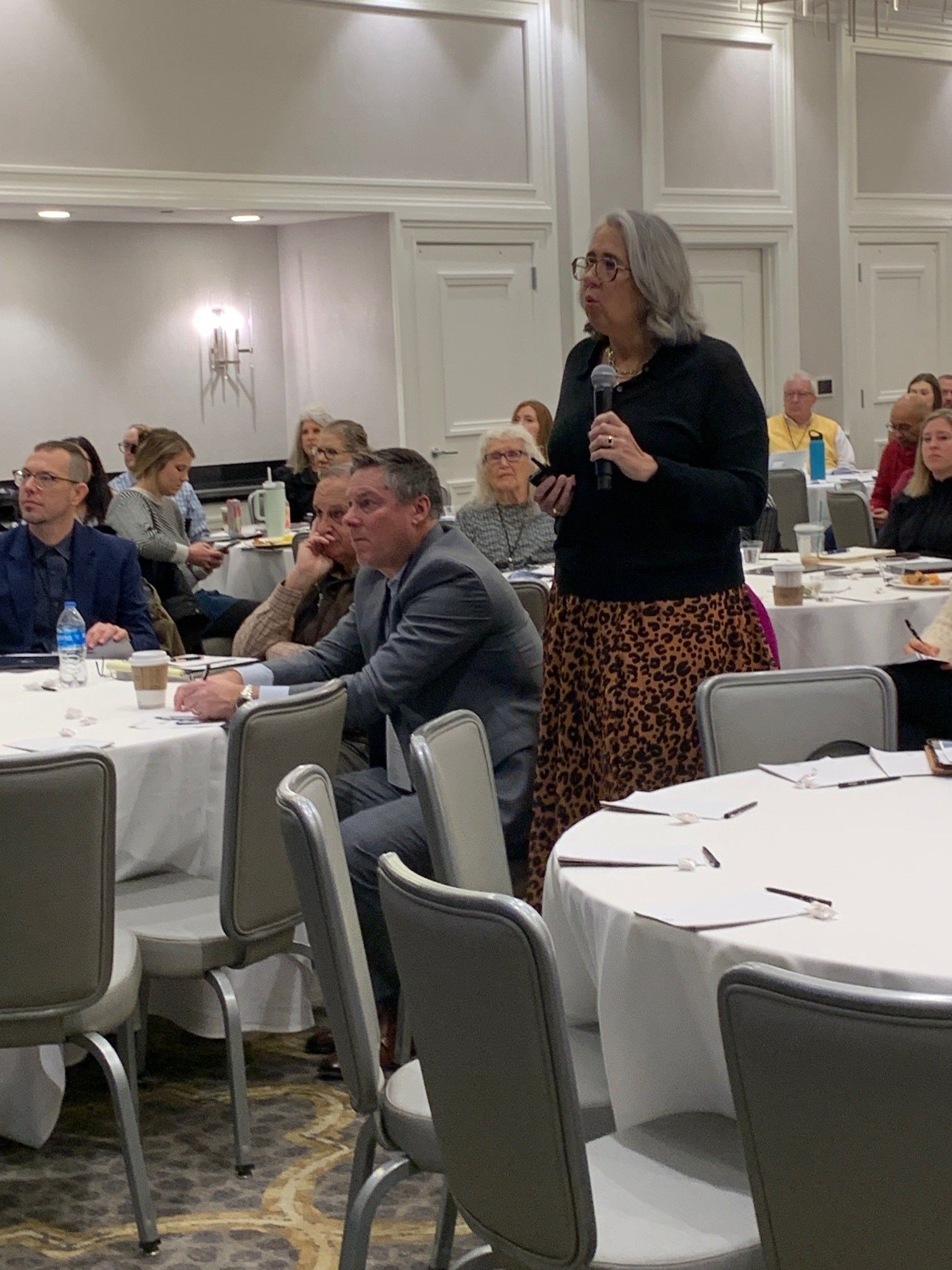 A woman is standing in front of a group of people at a conference.
