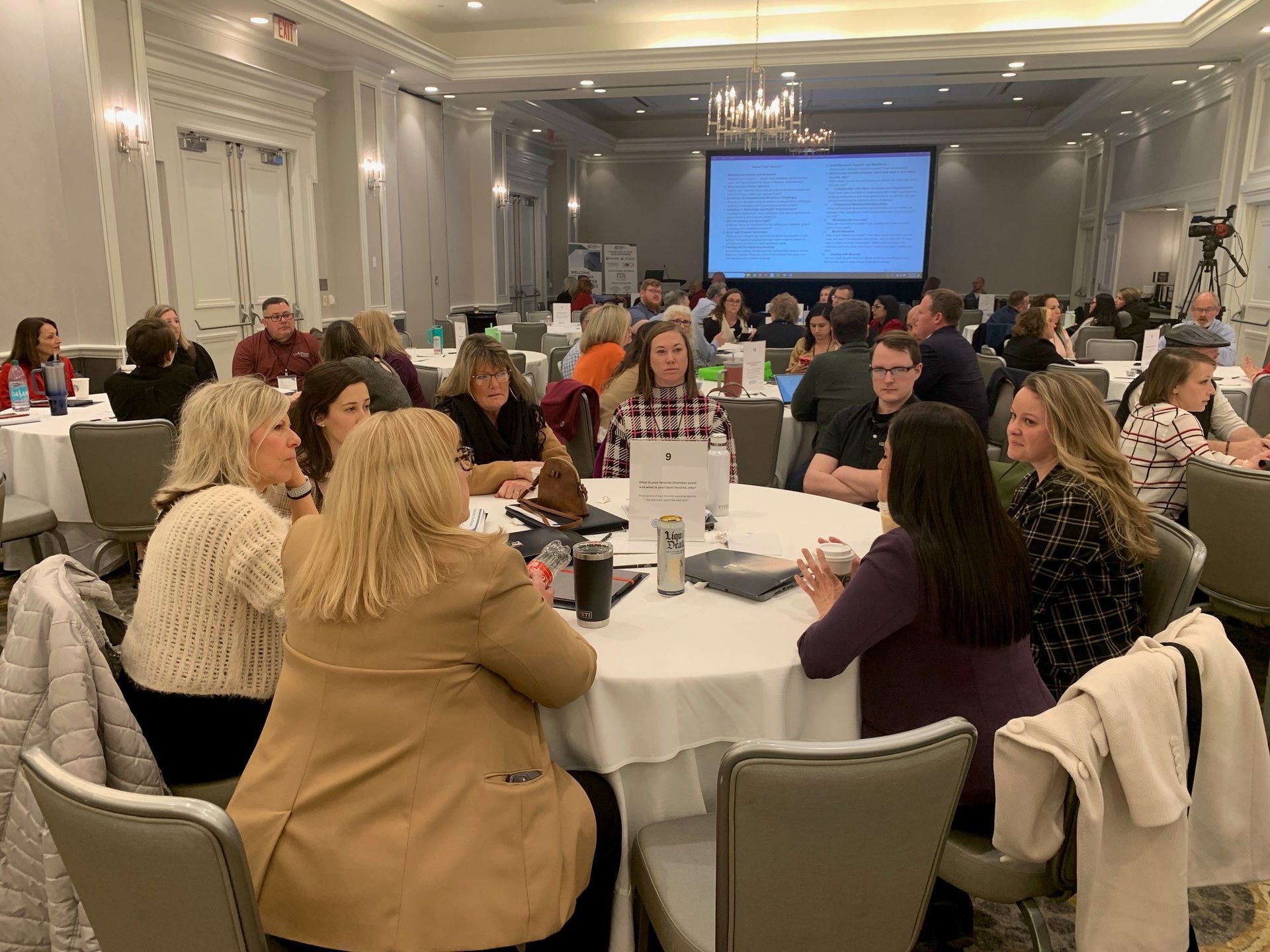 A group of people are sitting at tables in a large room.
