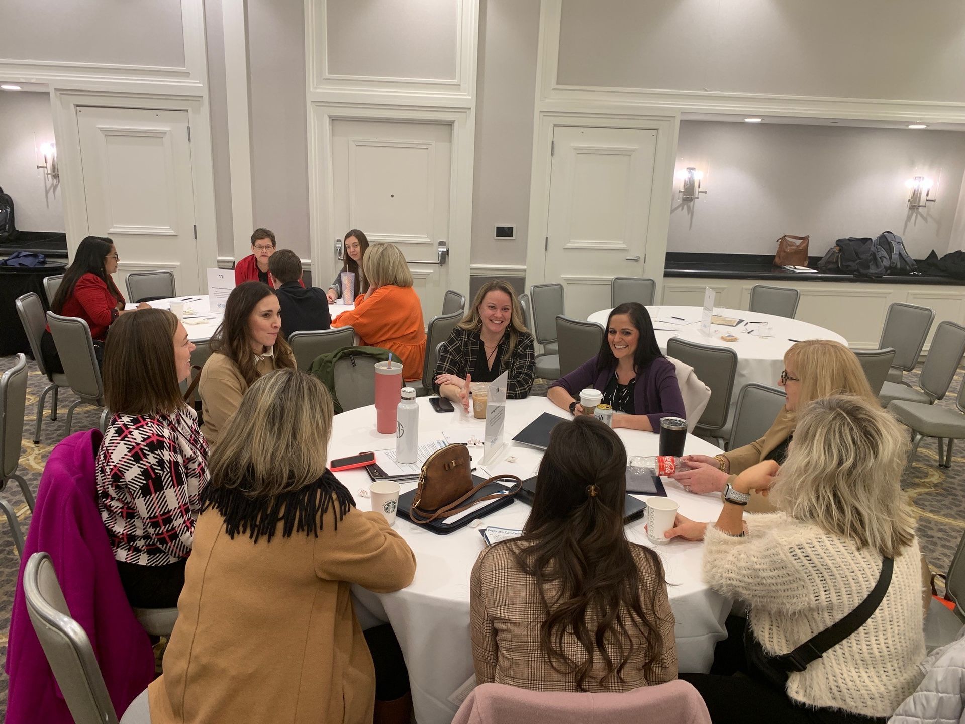 A group of women are sitting around a table in a room.