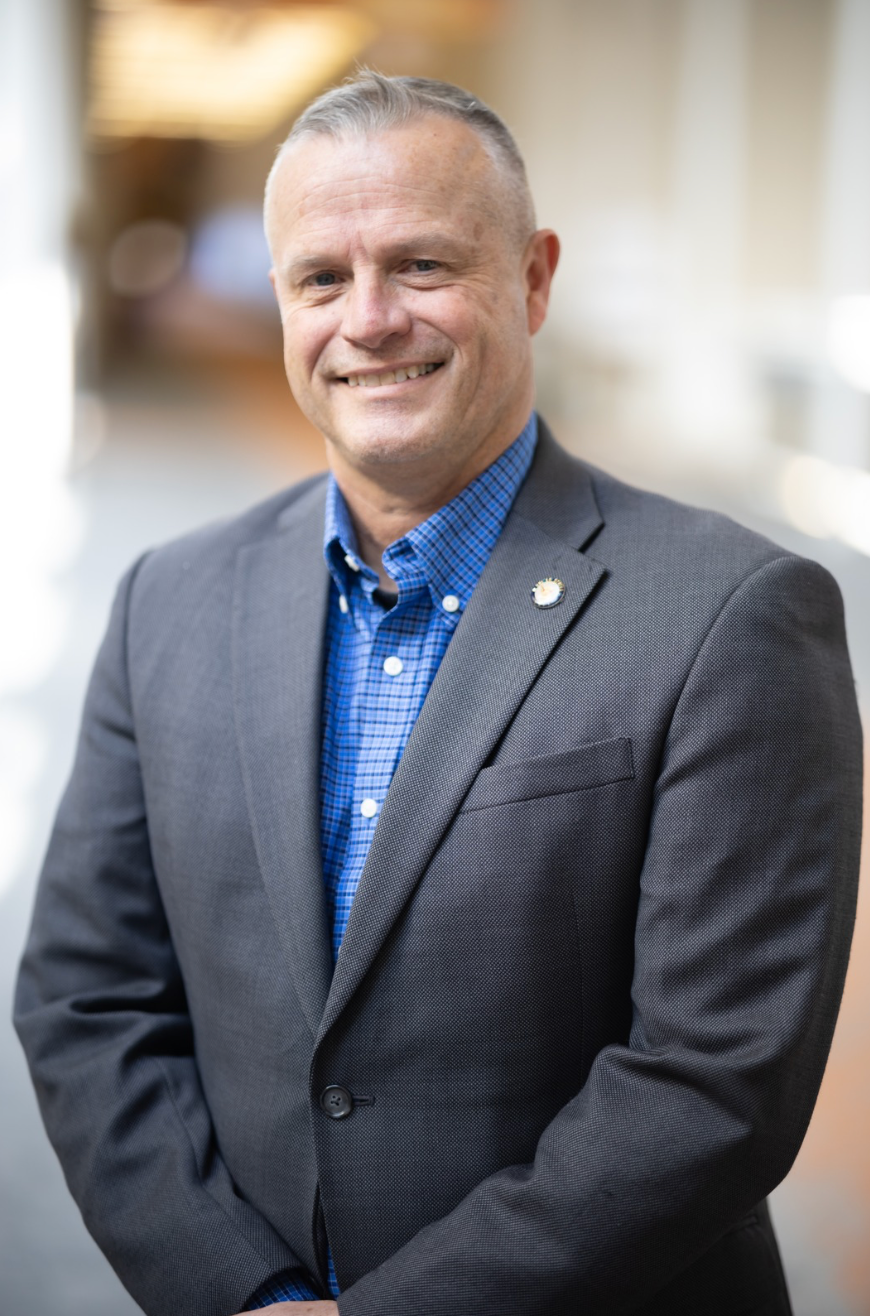A man in a suit and blue shirt is smiling for the camera.