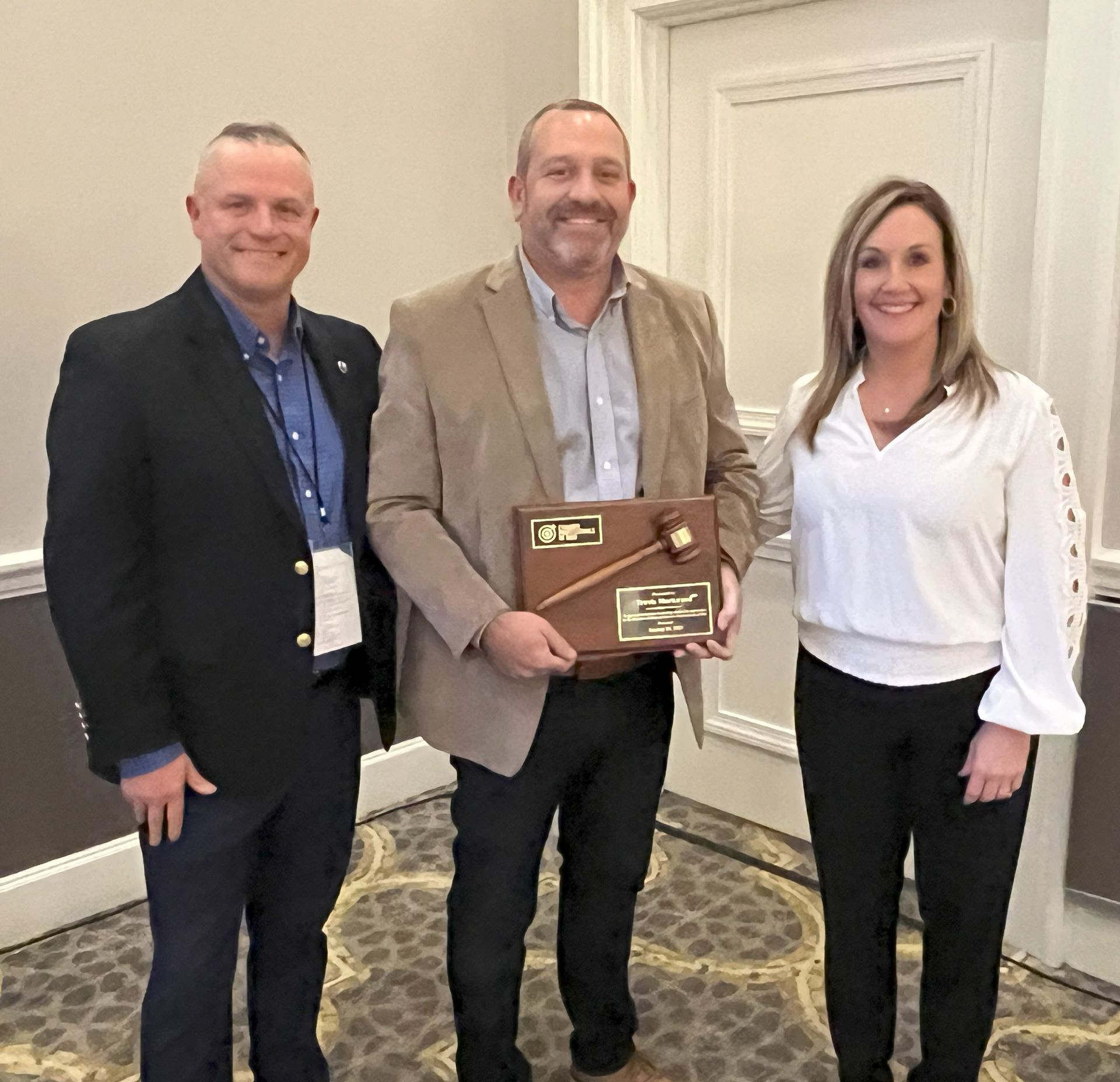 Three people are standing next to each other and one of them is holding a plaque.