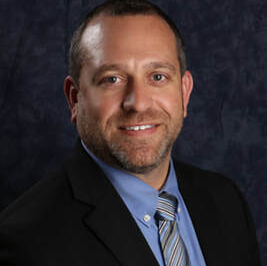A man in a suit and tie is smiling for the camera.