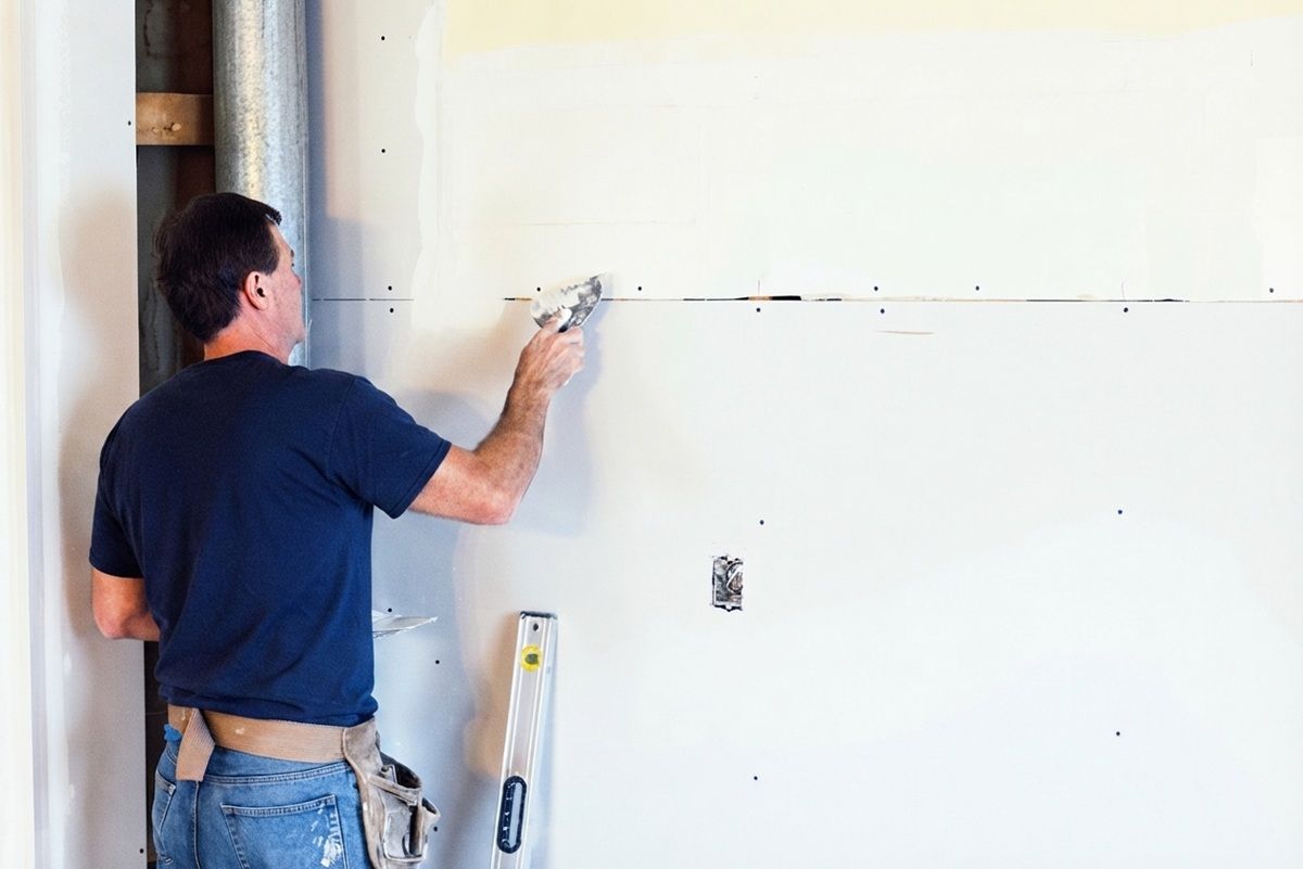 Technician finishing drywall joints on a Merced installation project