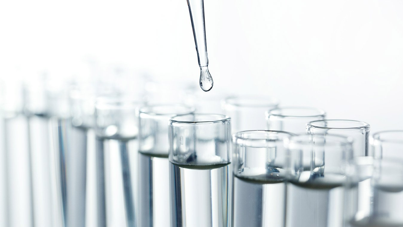 A drop of liquid is being poured into a test tube.