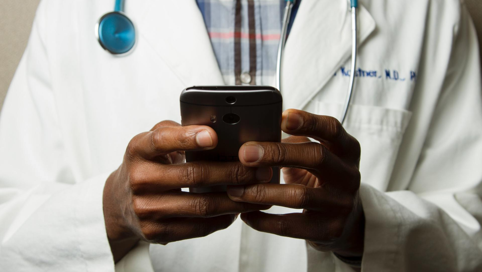 A doctor is holding a cell phone in his hands.