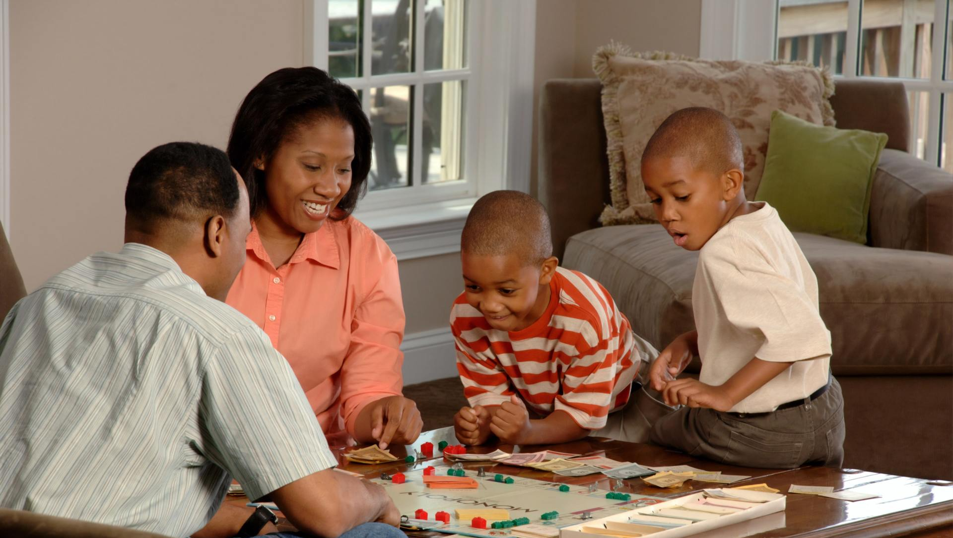 A family is playing a board game together in a living room
