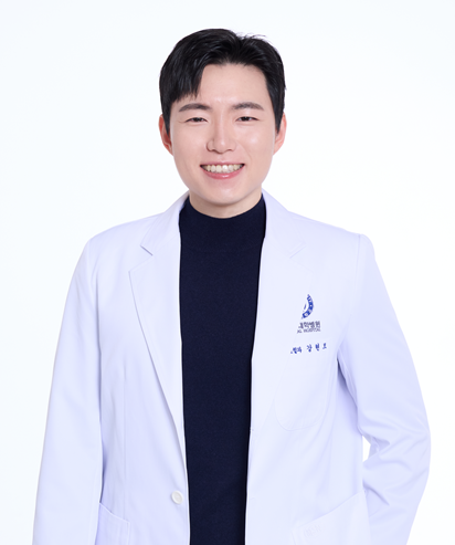 A smiling woman wearing a white lab coat, arms crossed, stands against a white background.