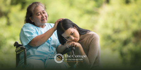 A woman resting his head on her senior mother's wheelchair