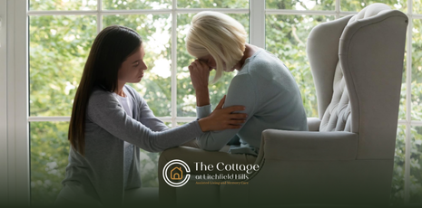 A family caregiver talking to a senior parent sitting on a couch