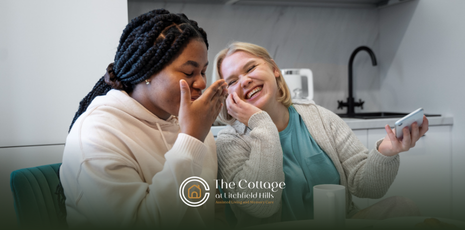 Two caregivers laughing together while eating