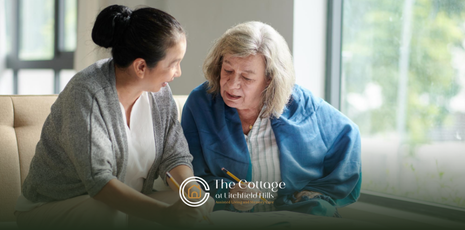 A senior talking to a caregiver, sitting on a couch together