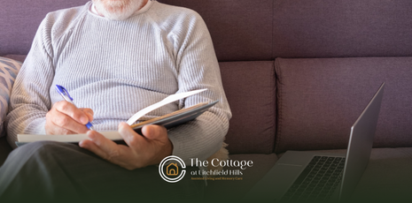 A senior sitting on a couch, journaling