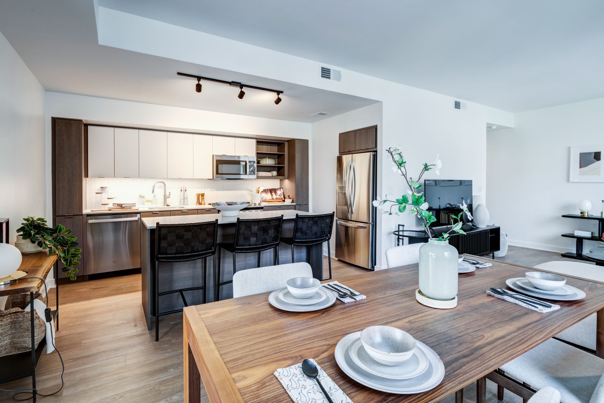 Open-plan kitchen and dining area with wooden table, black stools, and light wood cabinets  at  Solaire 7607 Old Georgetown in Bethesda, MD