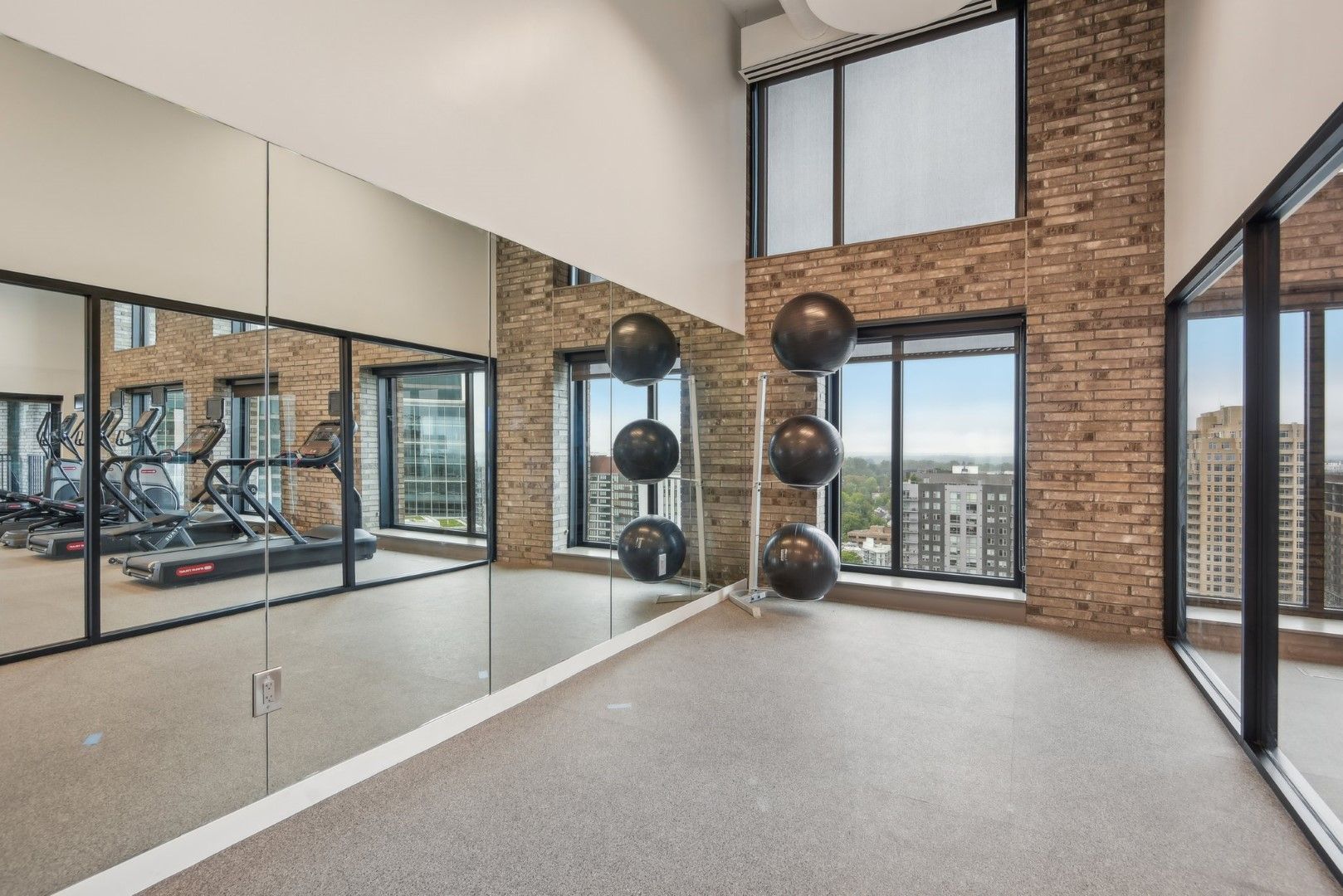 A gym with a treadmill , exercise balls , and a large mirror.