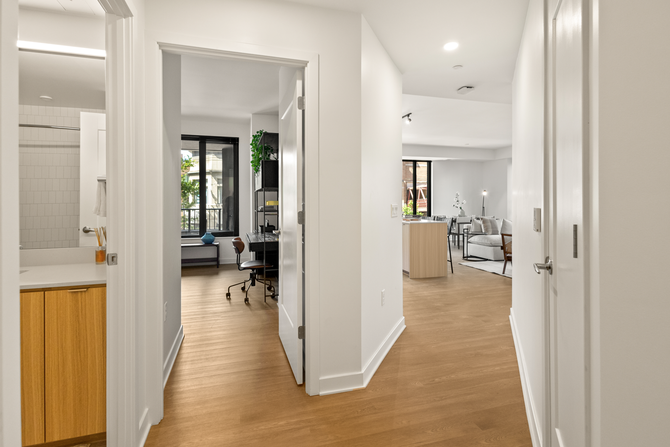 A hallway in a house with hardwood floors and white walls leading to a living room  at  Solaire 7607 Old Georgetown in Bethesda, MD
