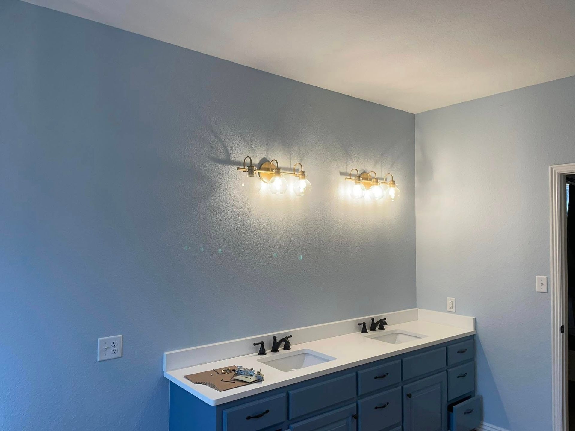 A bathroom with two sinks and two lights on the wall.