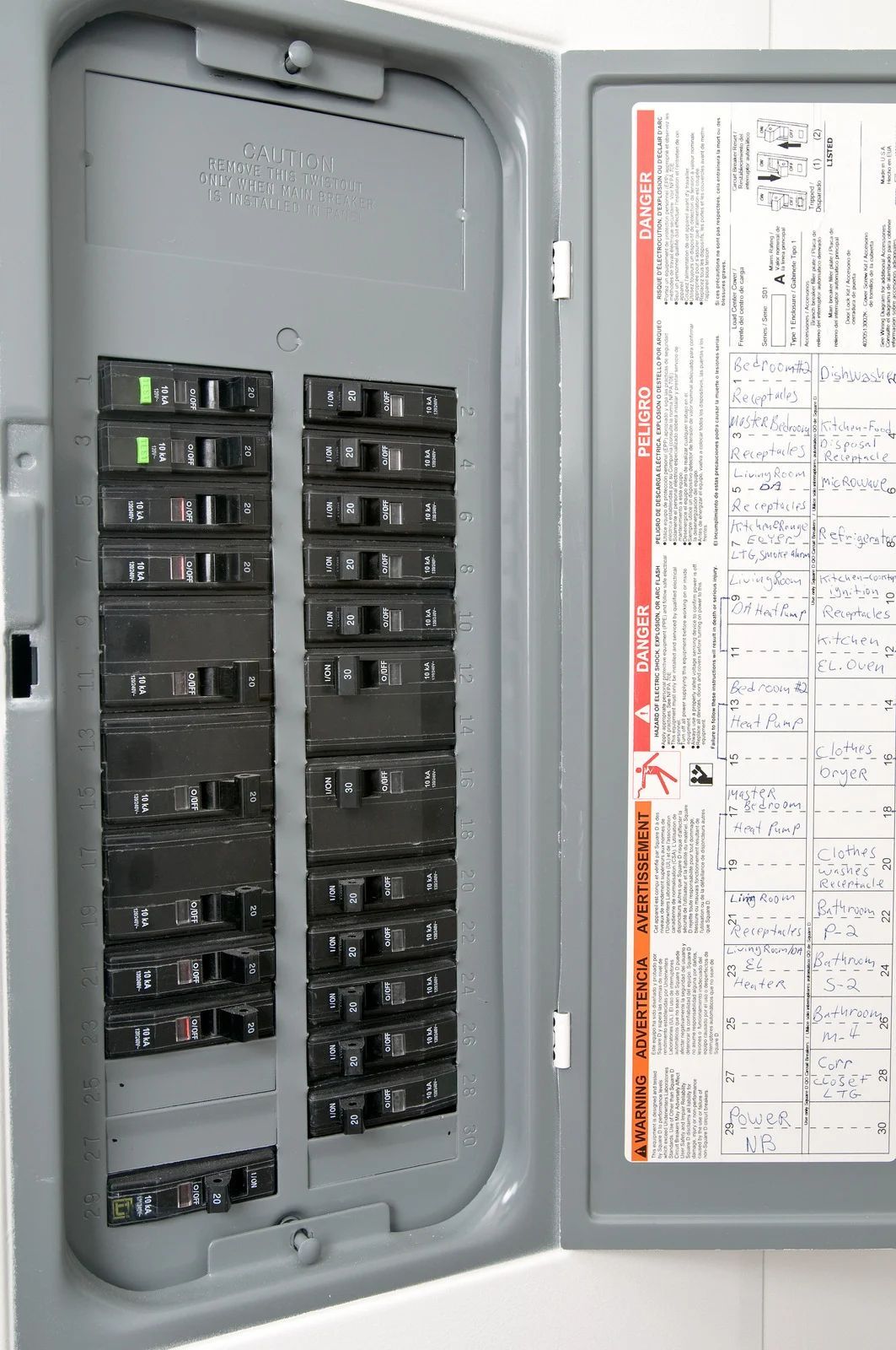 Open electrical breaker panel with rows of black circuit breakers and a panel schedule on the door.