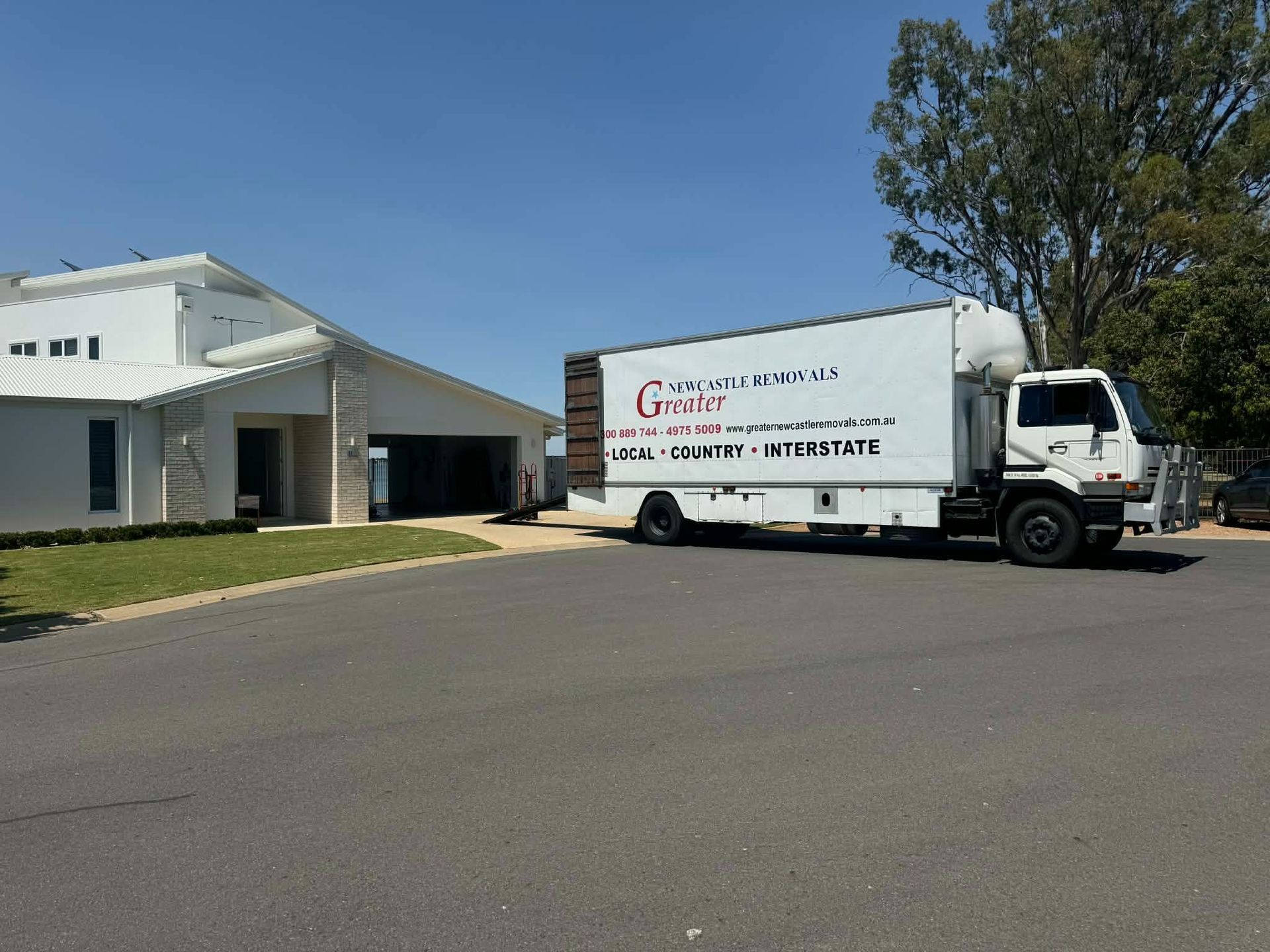White delivery truck parked beside a house on a sunny street