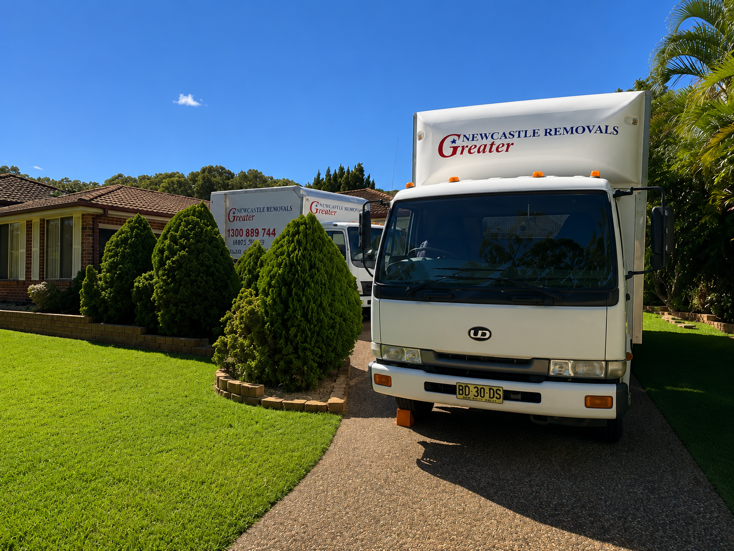 White delivery truck parked beside a modern gray building on a sunny street.