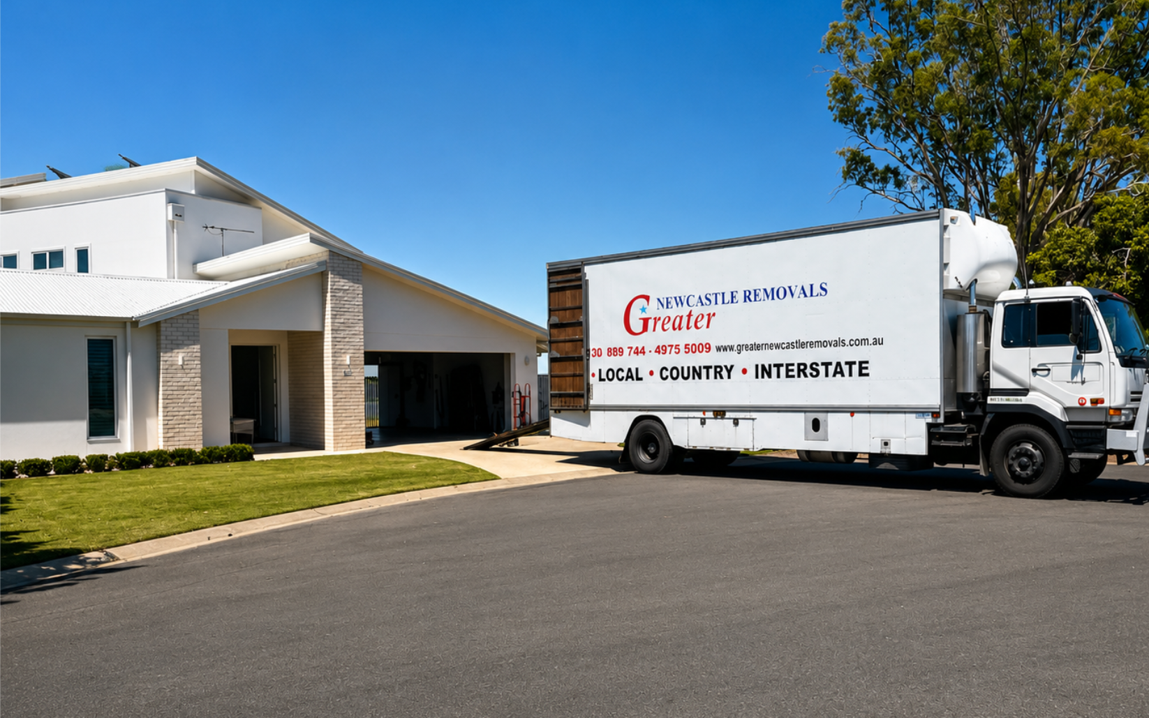White delivery truck parked beside a modern white building under a clear blue sky
